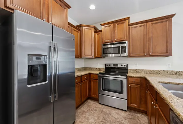 a kitchen with stainless steel appliances granite countertop a sink refrigerator and cabinets