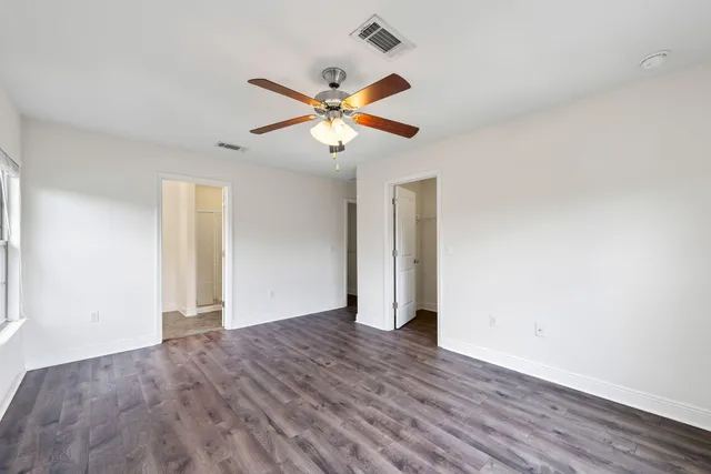 an empty room with wooden floor ceiling fan and window