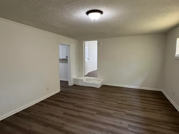 a view of an empty room with wooden floor and windows