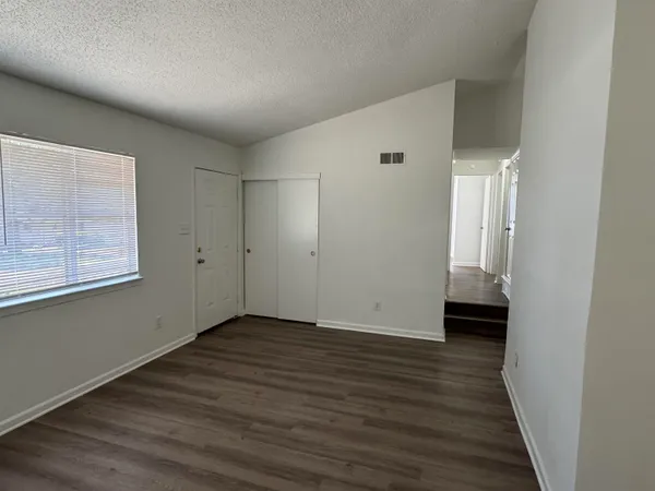 a view of an empty room with wooden floor and a window