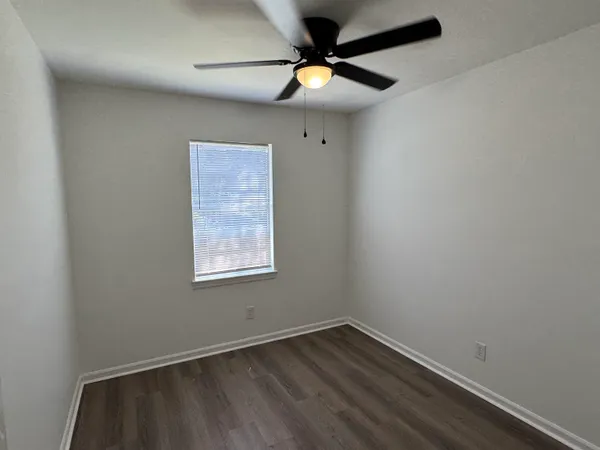 an empty room with a window and a fan