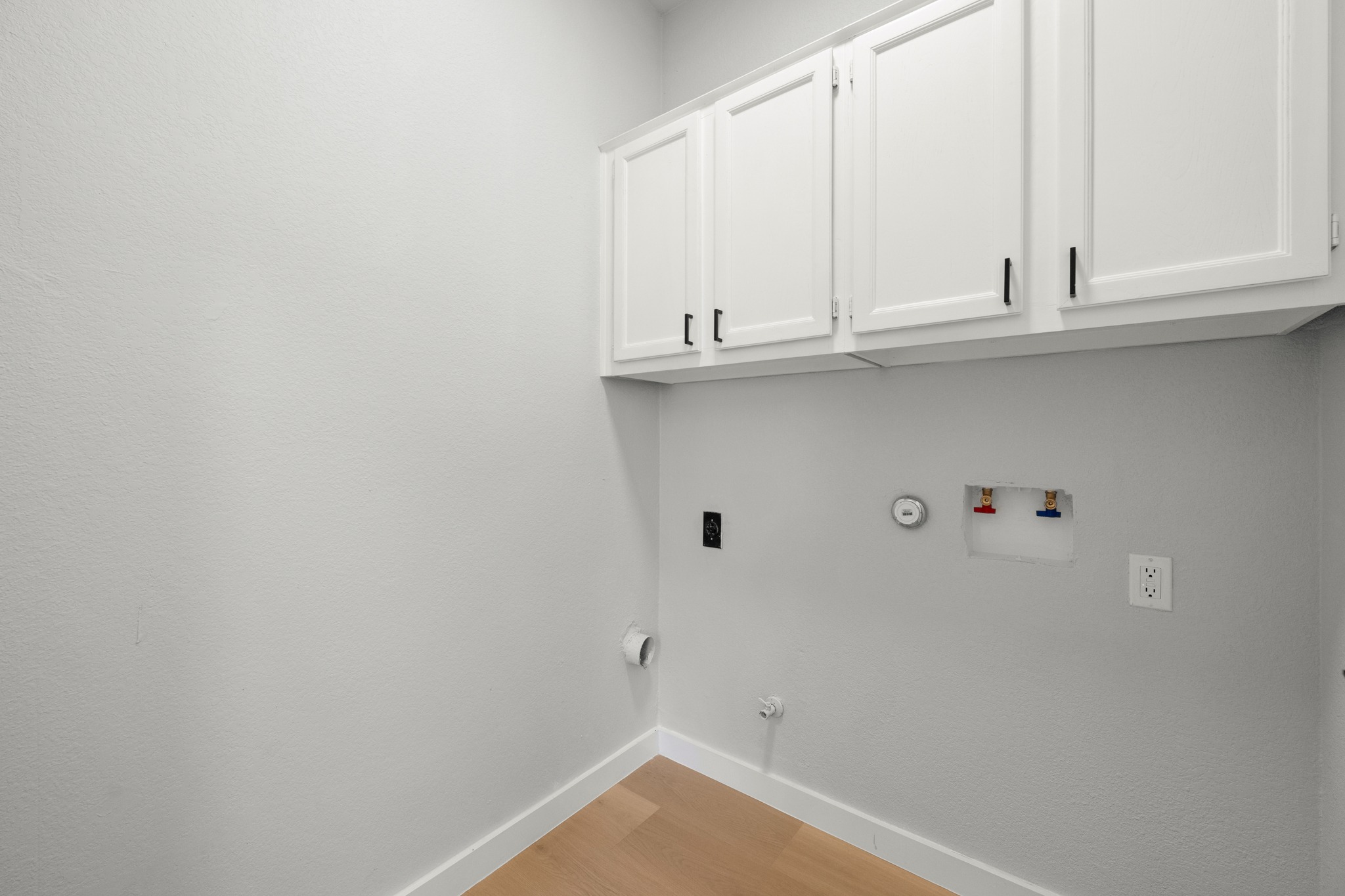 6501 Brush Country Road, Unit 120 Austin, TX 78749 - Photo 19 of 26 Large laundry room featuring white shaker-style cabinetry with matte black hardware, light wood-finish flooring, and crisp white baseboards