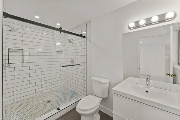 a bathroom with a shower sink vanity mirror and toilet