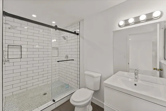 a bathroom with a shower sink vanity mirror and toilet