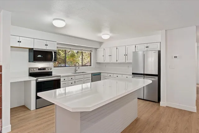 a kitchen with a refrigerator a stove top oven a sink dishwasher and wooden floor