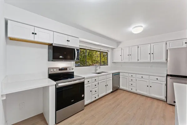 a kitchen with white cabinets appliances and sink