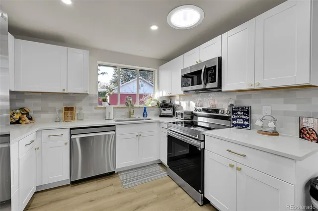 a kitchen with white cabinets stainless steel appliances and sink