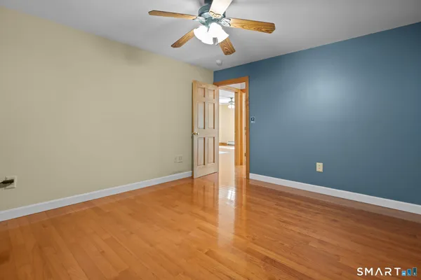 an empty room with wooden floor chandelier fan and windows