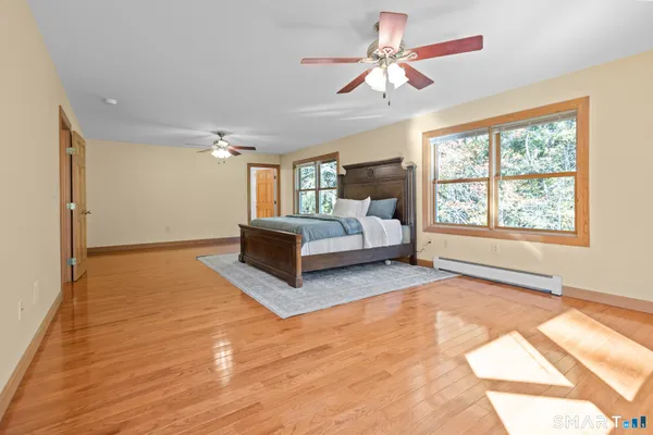 a spacious bedroom with a large bed a chandelier and windows