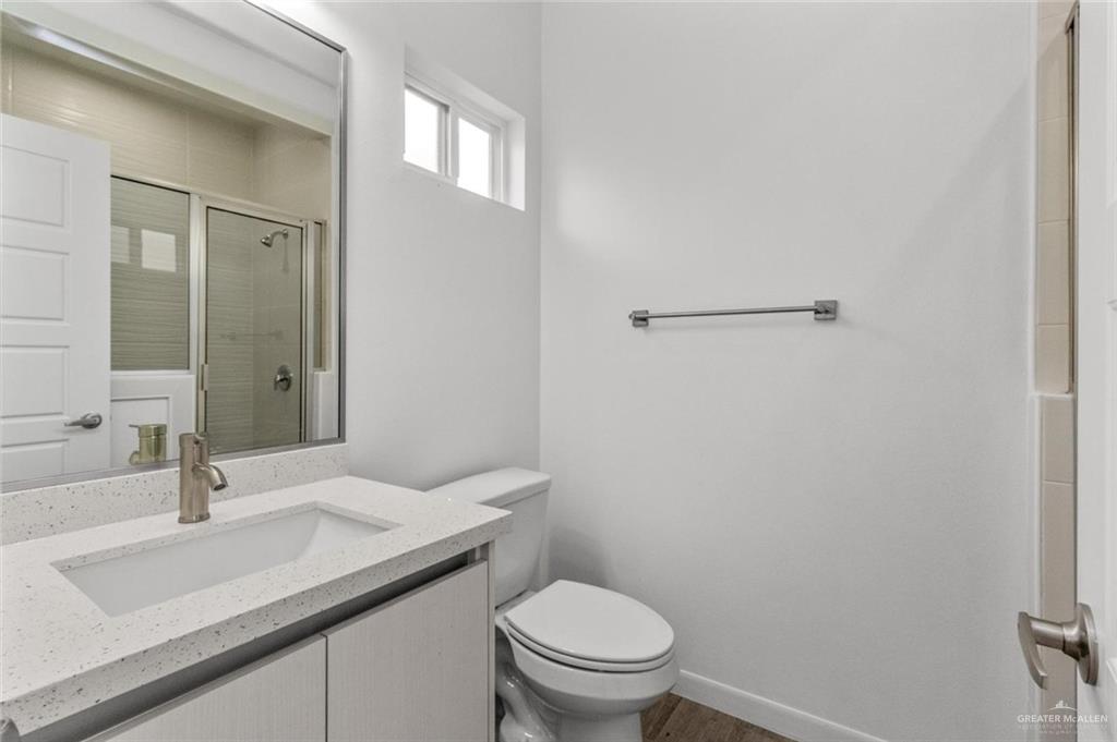 304 West Campeche Avenue, Unit 3 Alton, TX 78573 - Photo 4 of 10 Full bathroom featuring a stall shower, wood finished floors, vanity, baseboards, and toilet