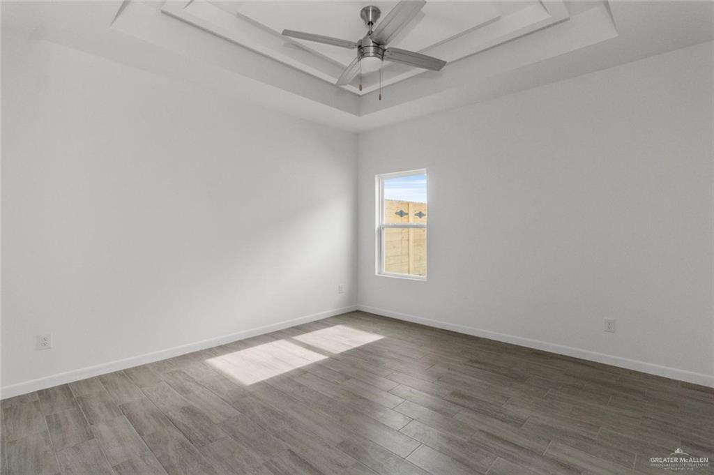 304 West Campeche Avenue, Unit 3 Alton, TX 78573 - Photo 7 of 10 Spare room with baseboards, a ceiling fan, a raised ceiling, and wood finished floors