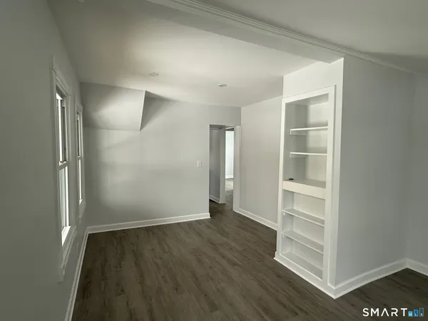 an empty room with wooden floor closet and windows