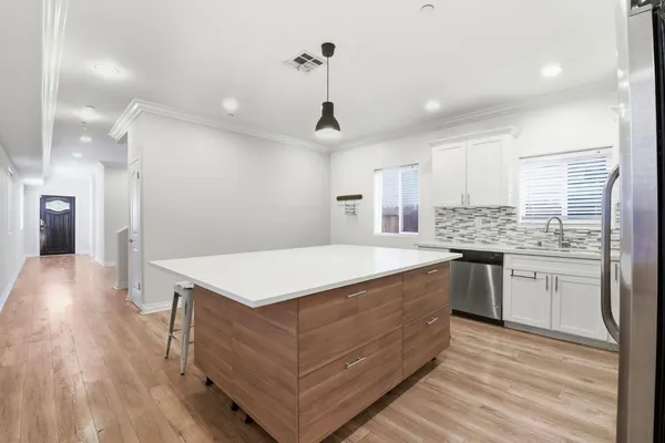 a kitchen that has a lot of cabinets in it and wooden floors