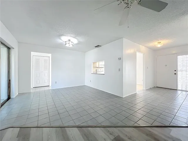 an empty room with wooden floor and a kitchen