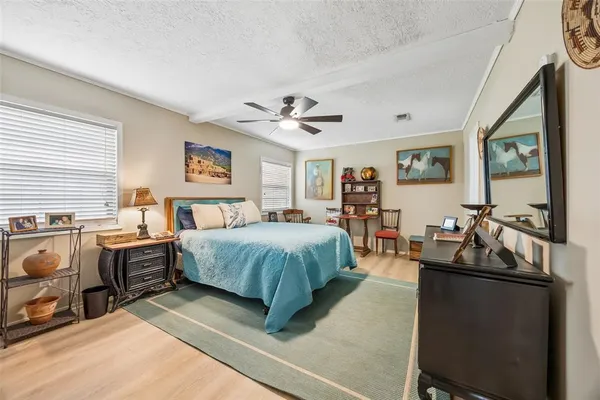 a spacious bedroom with a bed a dresser next to a window