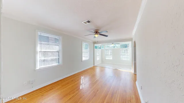 a view of an empty room with wooden floor and a window