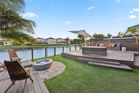 a view of a patio with couches chairs and a table and chairs with wooden floor and fence