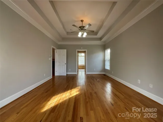 a view of an empty room with window and wooden floor