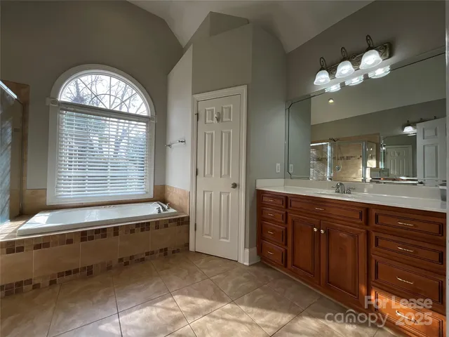 a spacious bathroom with a granite countertop sink a large mirror and a bathtub with shower