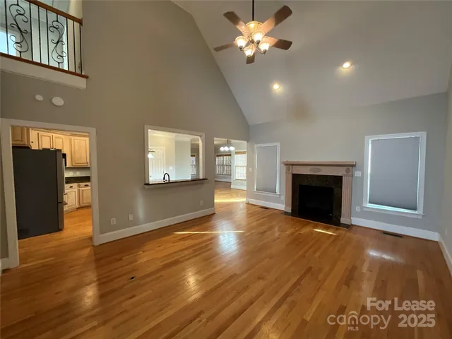 a view of an empty room with wooden floor and a fireplace