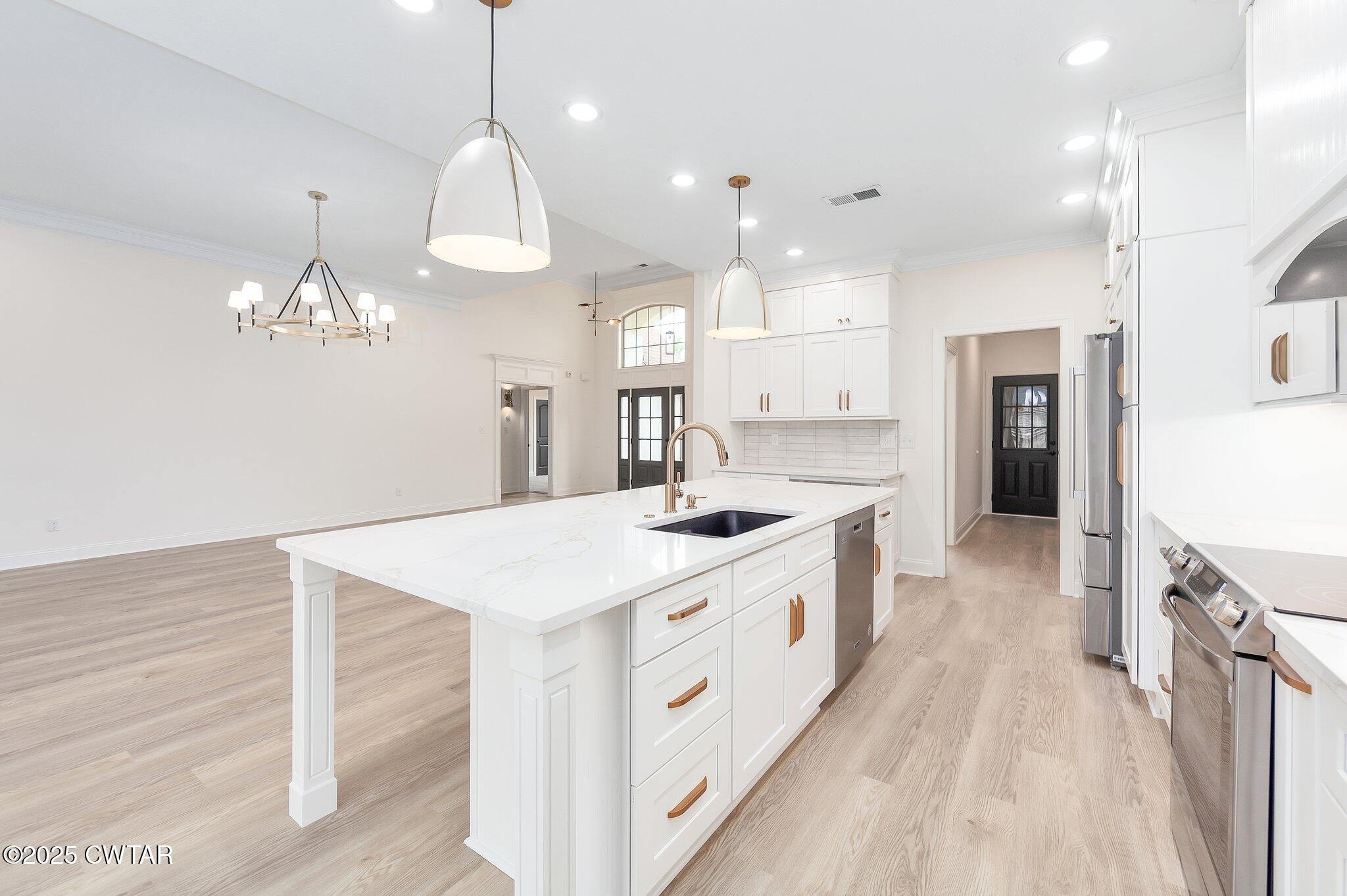 24 Joseph Cove Jackson, TN 38305 - Photo 35 of 37 a large kitchen with kitchen island a stove a sink a center island and a chandelier