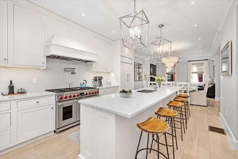 a large kitchen with stainless steel appliances a stove a sink a dining table and chairs