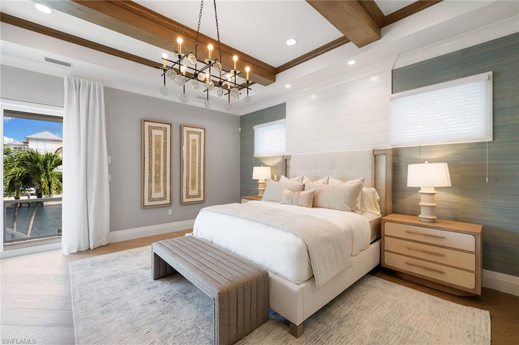 175 Conners Avenue Naples, FL 34108 - Photo 19 of 49 a spacious bedroom with a bed and a chandelier