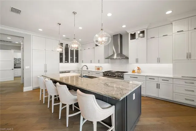 a kitchen with kitchen island granite countertop a sink and white cabinets