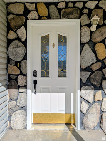 441 Main Street Hurricane, UT 84737 - Photo 3 of 29 White entry door with decorative glass inserts, surrounded by a stone facade and featuring a wall-mounted exterior light fixture