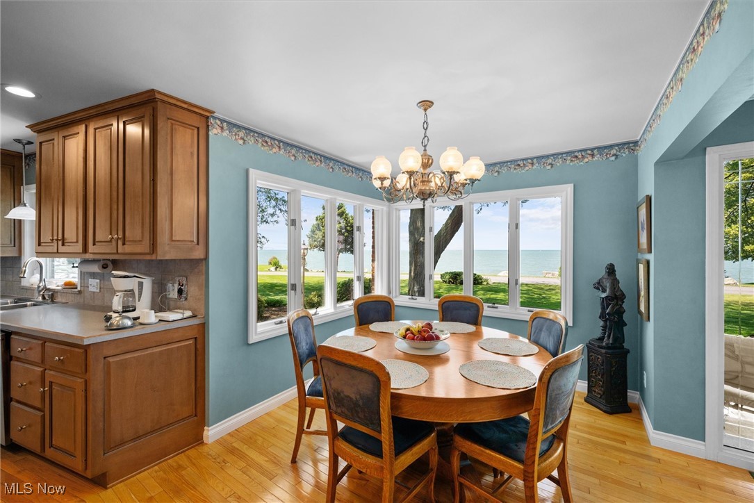 4520 East Cliff Road Port Clinton, OH 43452 - Photo 28 of 50 Dining space featuring light wood finished floors, healthy amount of natural light, a water view, and a chandelier