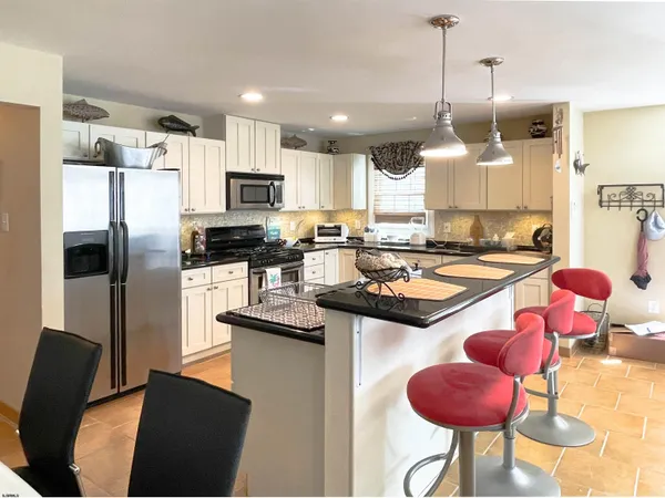 a kitchen with stainless steel appliances granite countertop a sink a stove a refrigerator a center island and cabinets