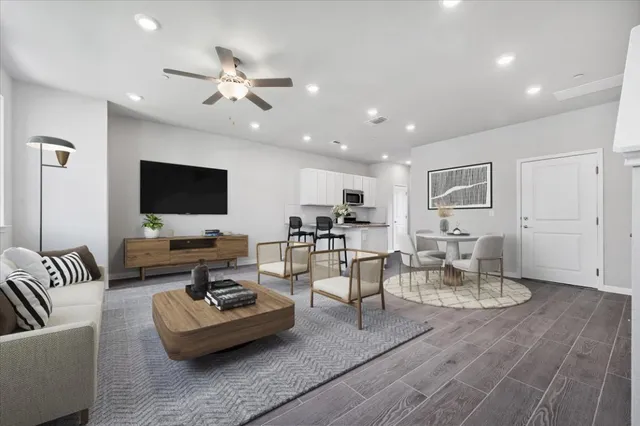 a view of an empty room with wooden floor and a ceiling fan
