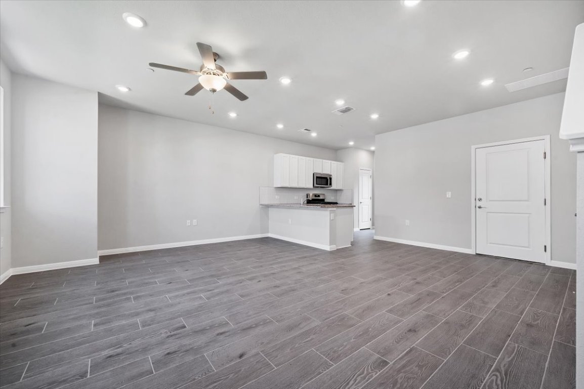 9015 Cattle Baron Path, Unit 1303 Austin, TX 78747 - Photo 4 of 14 a view of an empty room with wooden floor and kitchen