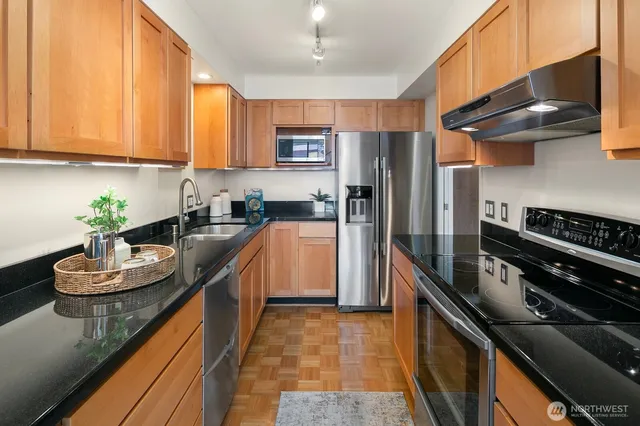 a kitchen with stainless steel appliances granite countertop a sink a stove and a refrigerator