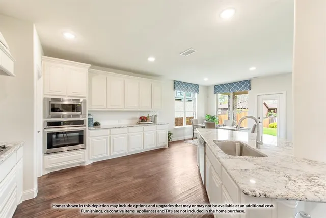 a kitchen with stainless steel appliances kitchen island granite countertop a refrigerator oven a sink dishwasher and white cabinets with wooden floor