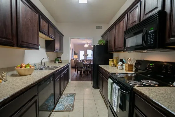 a kitchen with granite countertop lots of stainless steel appliances granite countertop a sink a stove and a wooden cabinets