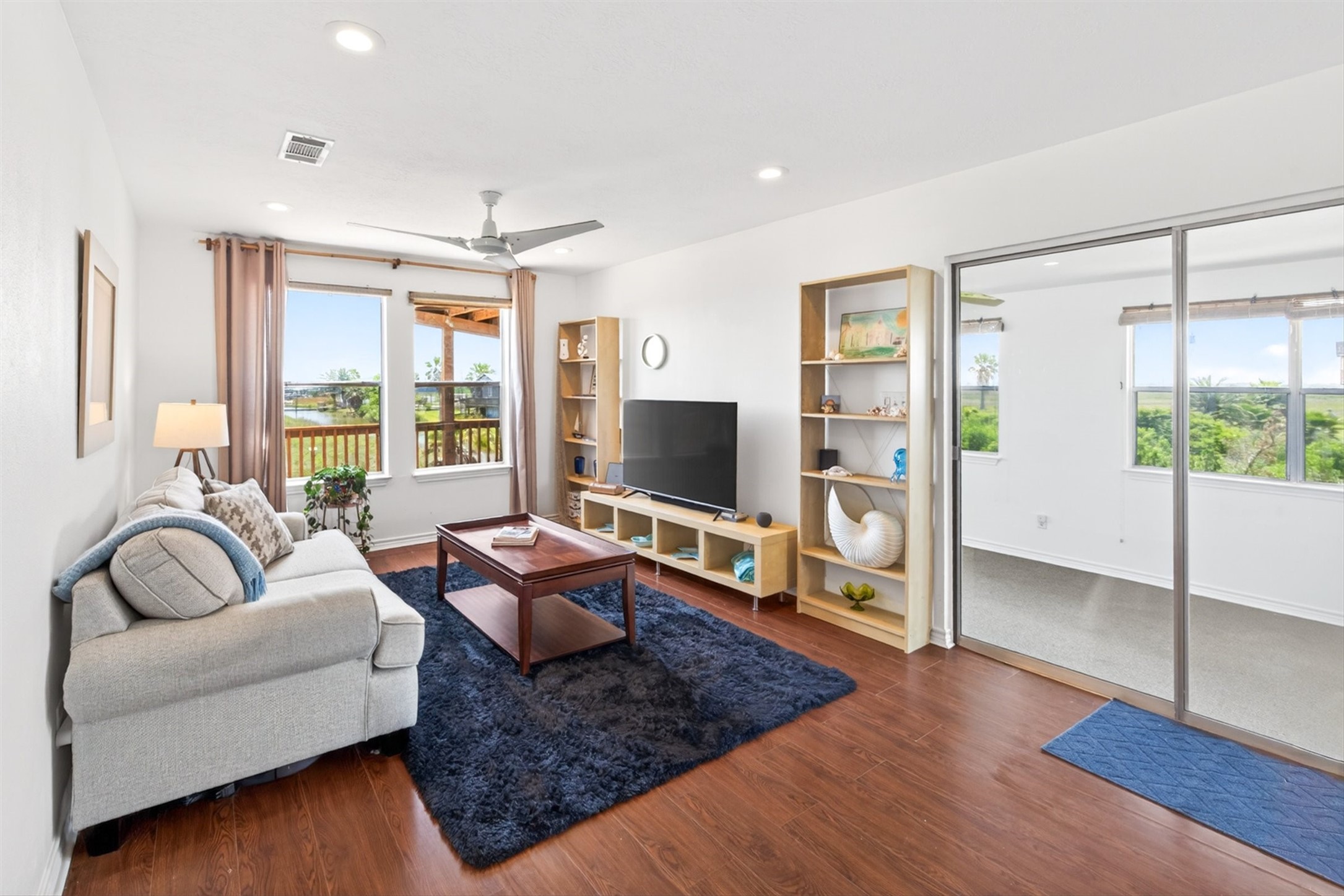 1209 North Jacks Road Crystal Beach, TX 77650 - Photo 11 of 39 Light-filled living space with warm flooring, open shelving, and sliding glass doors leading to a flexible bonus room—all framed by peaceful coastal views.