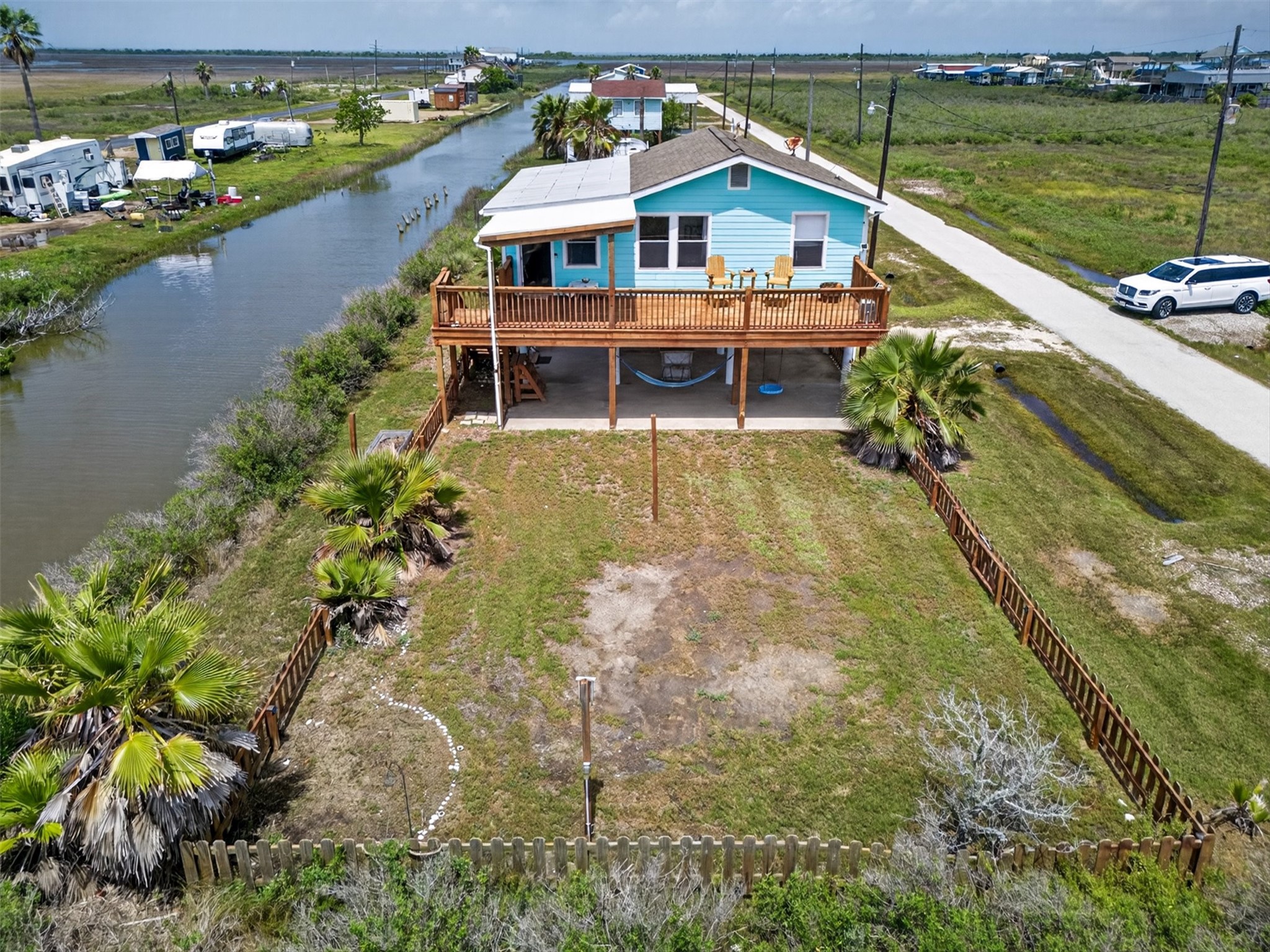 1209 North Jacks Road Crystal Beach, TX 77650 - Photo 2 of 39 Front aerial showcasing canal-front positioning, fenced yard, and direct access to the water—perfect for fishing, kayaking, or relaxing by the shore.