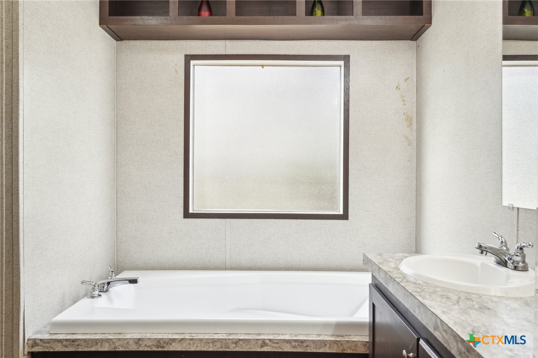 151 Deer River Drive Spring Branch, TX 78070 - Photo 20 of 29 a bathroom with a granite countertop sink and a bathtub