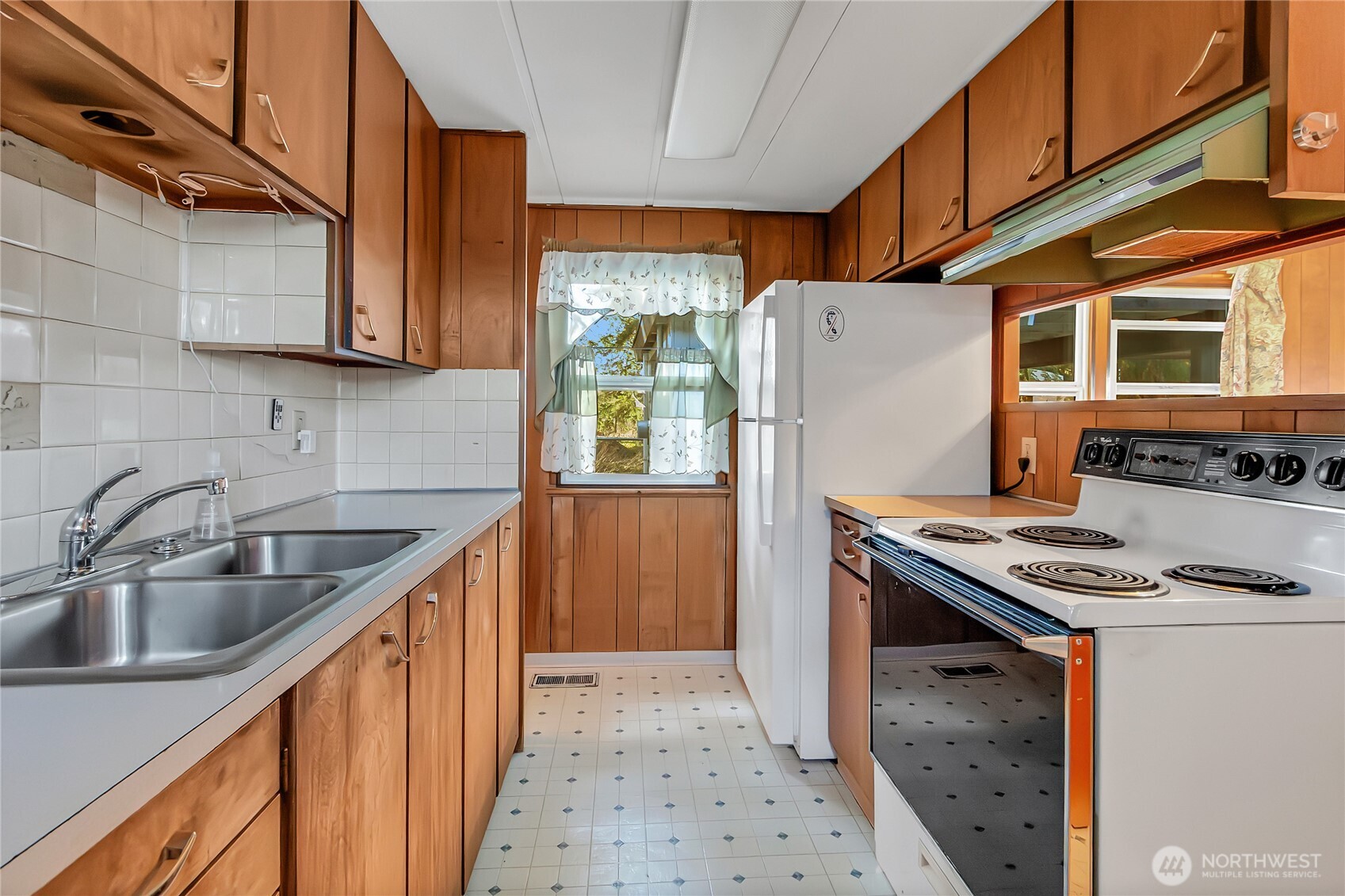 9314 Canyon Road East, Unit 34 Puyallup, WA 98371 - Photo 12 of 18 a kitchen with stainless steel appliances a refrigerator a sink and wooden cabinets