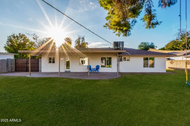 a view of a white house with a big yard and a large tree