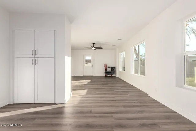 a view of empty room with wooden floor and fan