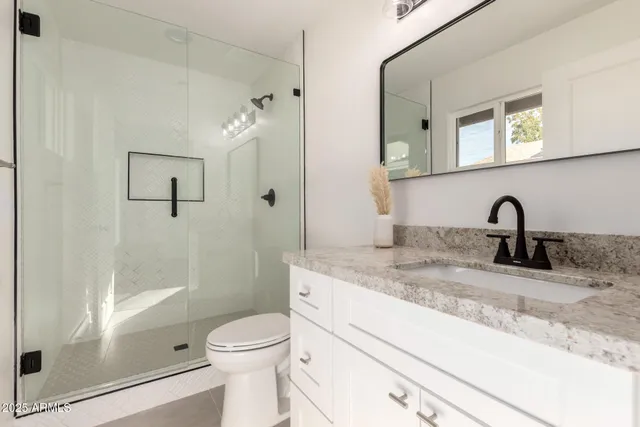 a bathroom with a granite countertop sink toilet and shower