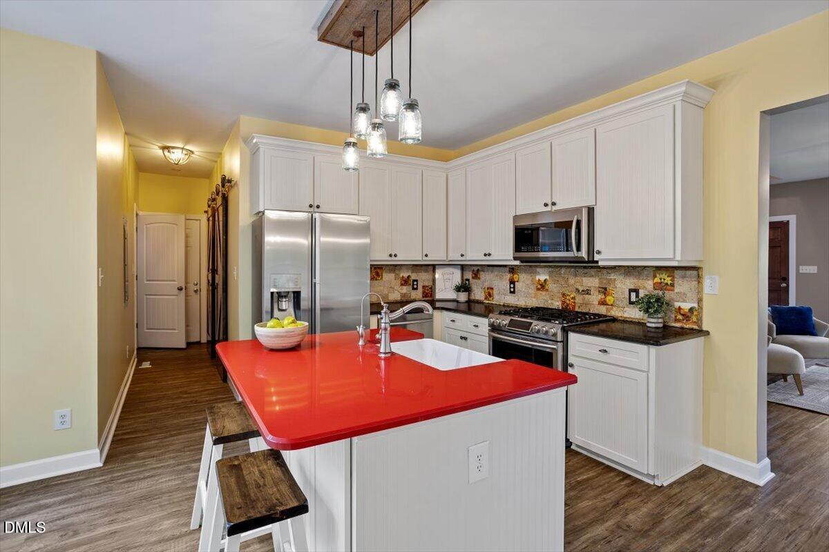 7505 Penny Road Raleigh, NC 27606 - Photo 17 of 35 a kitchen with stainless steel appliances granite countertop a refrigerator a stove top oven a sink dishwasher a dining table and chairs with wooden floor
