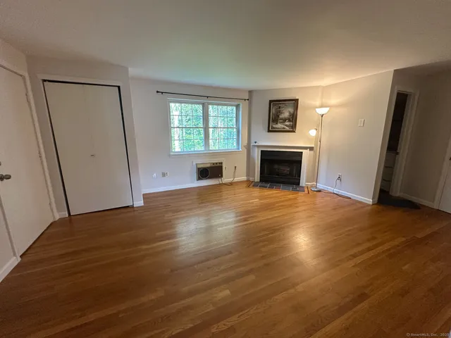 an empty room with windows fireplace and wooden floor