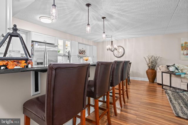 a kitchen with stainless steel appliances a refrigerator a stove a sink dishwasher a dining table and chairs with wooden floor