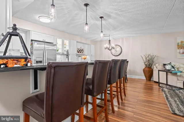 a kitchen with stainless steel appliances a refrigerator a stove a sink dishwasher a dining table and chairs with wooden floor