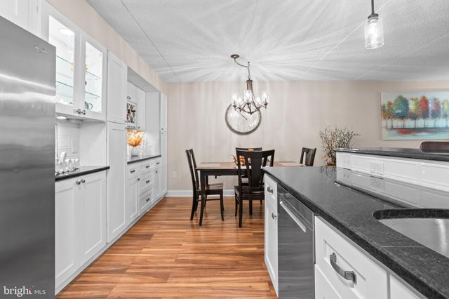 a kitchen with kitchen island granite countertop a sink a counter space appliances and cabinets