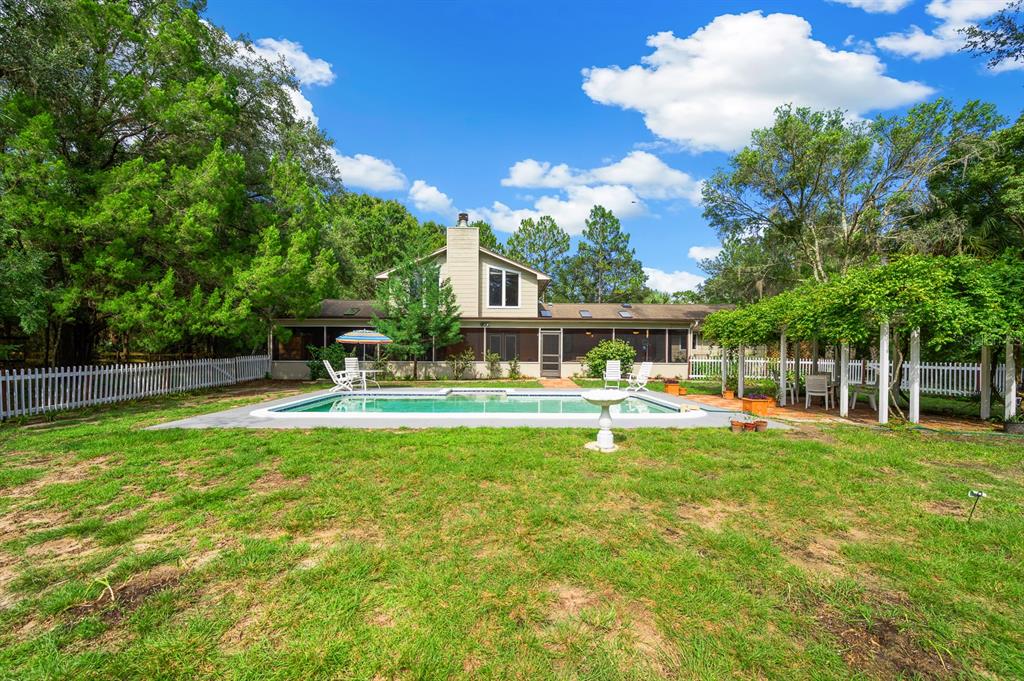 7201 Southwest 97th Lane Gainesville, FL 32608 - Photo 48 of 68 a view of a swimming pool with a table and chairs under an umbrella