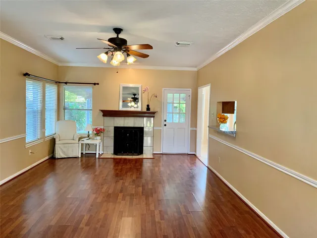 a view of a livingroom with a fireplace a ceiling fan and wooden floor